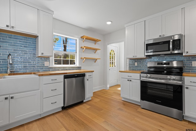 kitchen featuring butcher block counters, stainless steel appliances, light wood-type flooring, and a sink
