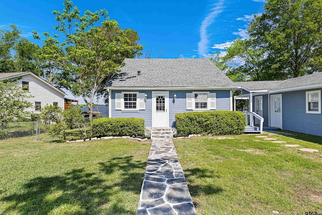 view of front of property with roof with shingles, fence, and a front lawn