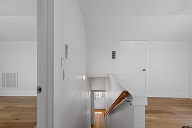 stairway featuring visible vents, baseboards, vaulted ceiling, and wood finished floors