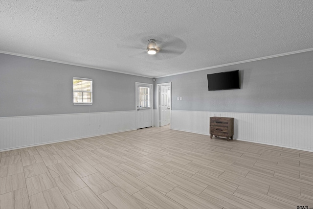 empty room featuring wainscoting, a textured ceiling, and a ceiling fan
