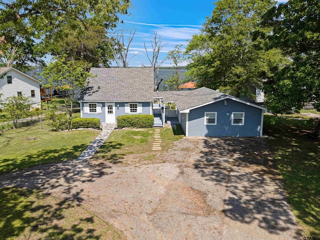 single story home featuring roof with shingles, driveway, and a front lawn