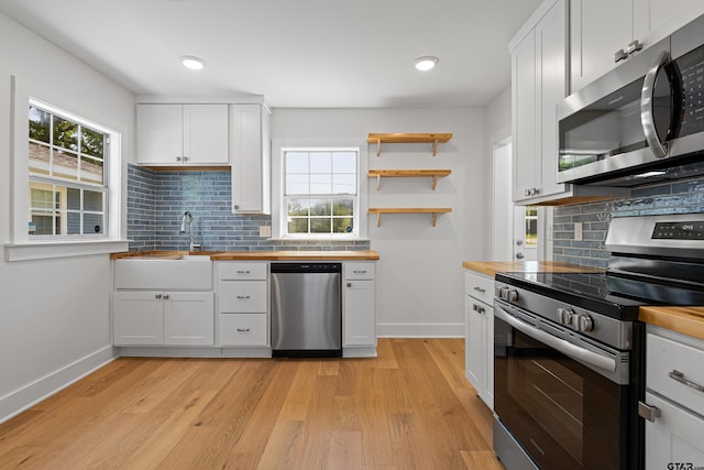 kitchen with plenty of natural light, light wood finished floors, appliances with stainless steel finishes, and wooden counters
