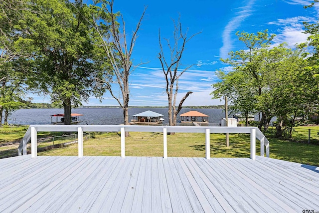 wooden terrace featuring a water view and a lawn