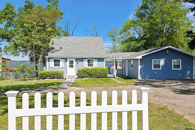 view of front of home with a front yard, roof with shingles, driveway, and a fenced front yard
