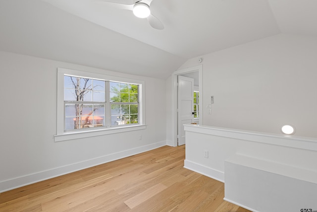 spare room with light wood-style floors, baseboards, a ceiling fan, and vaulted ceiling