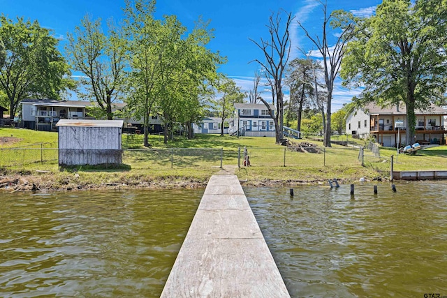 dock area featuring a yard, fence, a residential view, and a water view