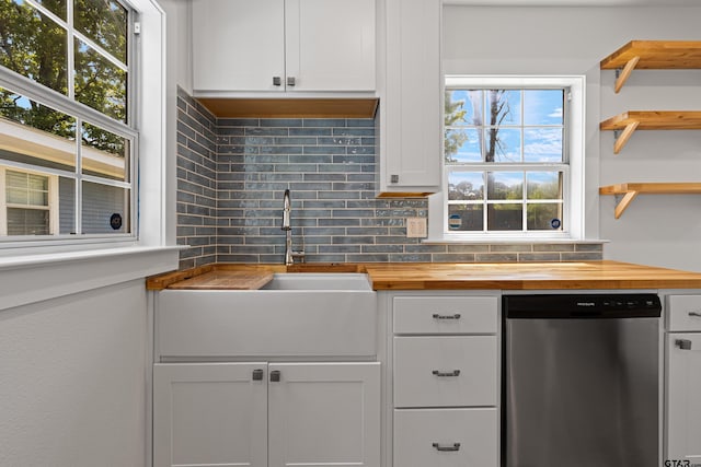 kitchen featuring tasteful backsplash, white cabinets, dishwasher, a sink, and butcher block countertops