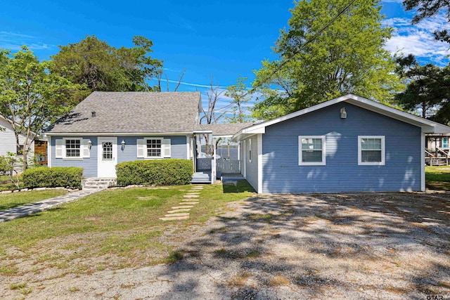 view of front of property featuring a front yard, a shingled roof, and gravel driveway