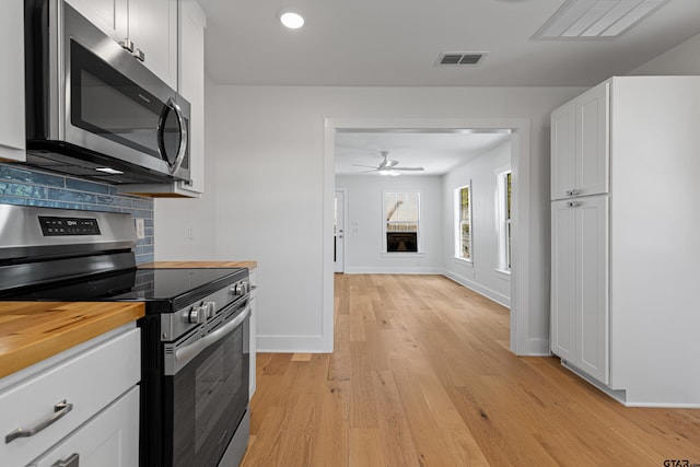 kitchen featuring wood counters, backsplash, white cabinets, appliances with stainless steel finishes, and light wood finished floors