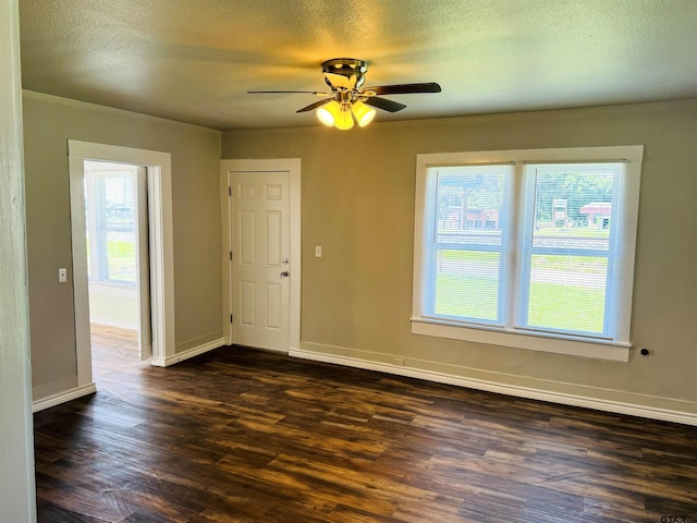 spare room featuring dark wood-type flooring, plenty of natural light, and a textured ceiling