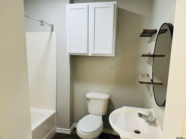 bathroom featuring shower / tub combination, a sink, toilet, and baseboards