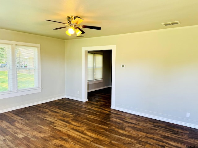 spare room featuring dark wood-style flooring, visible vents, and baseboards