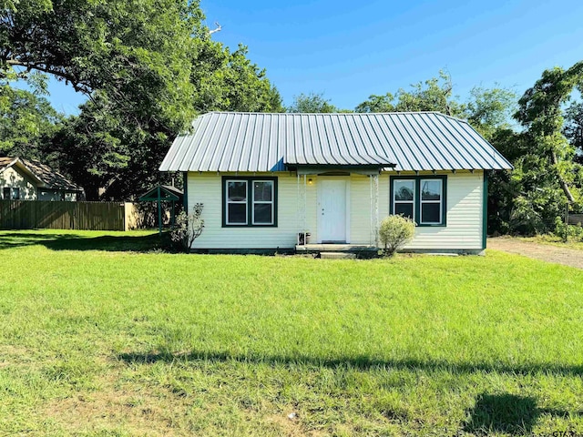 bungalow with metal roof, fence, and a front lawn