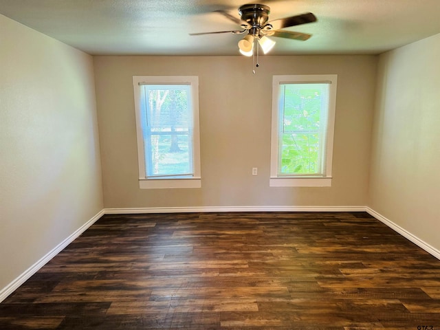 unfurnished room with baseboards, dark wood-type flooring, and a wealth of natural light