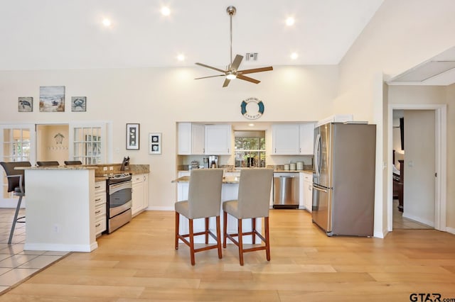 kitchen with white cabinets, a kitchen breakfast bar, a kitchen island, and appliances with stainless steel finishes