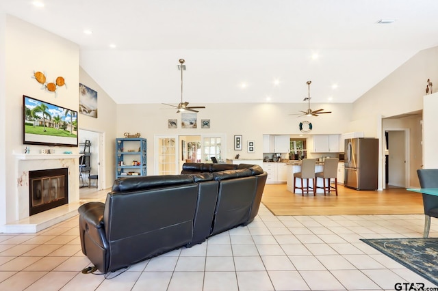 living room with a high end fireplace, lofted ceiling, and light tile patterned flooring