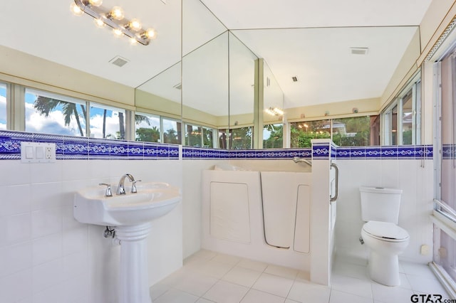 bathroom featuring tile patterned flooring, tile walls, and toilet