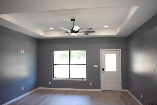 foyer entrance with a raised ceiling, ceiling fan, and light hardwood / wood-style flooring