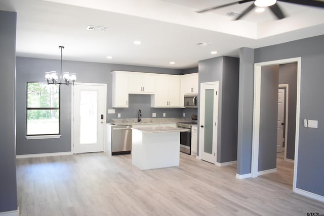 kitchen with white cabinetry, sink, light hardwood / wood-style flooring, a kitchen island, and appliances with stainless steel finishes