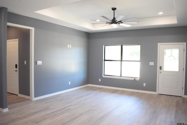 foyer entrance featuring ceiling fan, a tray ceiling, and light hardwood / wood-style flooring