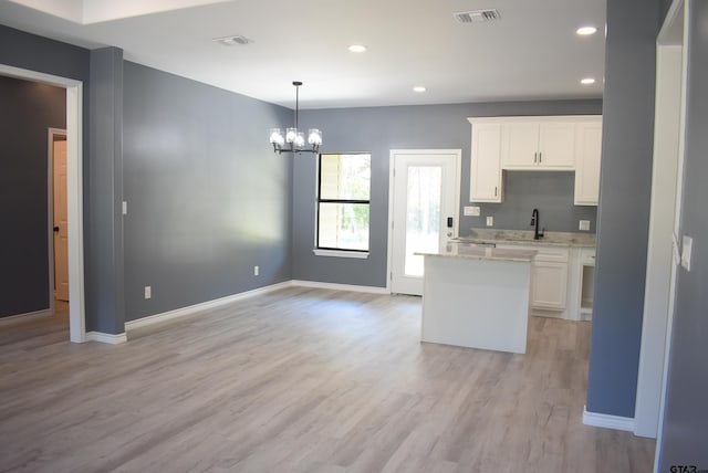 kitchen with white cabinetry, sink, hanging light fixtures, a notable chandelier, and light hardwood / wood-style floors