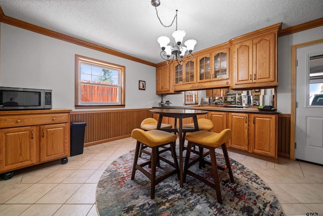 8312 Oxford Dr, Tyler, TX 75703 - dining room featuring crown molding, a chandelier, wainscoting, a textured ceiling, and light tile patterned floors