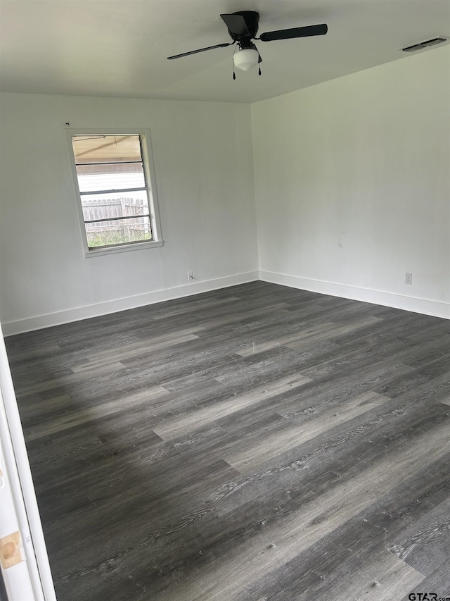 empty room with ceiling fan, visible vents, dark wood-style floors, and baseboards