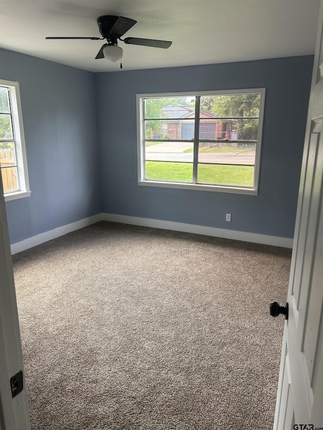 carpeted spare room with baseboards and a ceiling fan