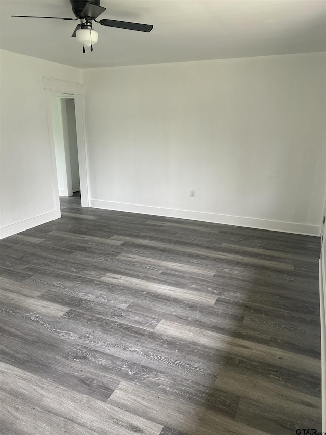 unfurnished room with baseboards, dark wood-style flooring, and ceiling fan