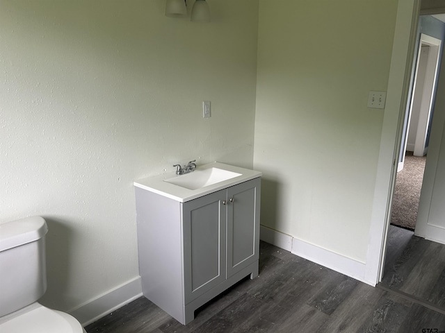 bathroom with baseboards, vanity, toilet, and wood finished floors