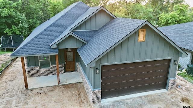 2514 N Glass, Tyler, TX 75702 - view of front facade featuring a shingled roof, board and batten siding, a trampoline, a garage, and covered porch