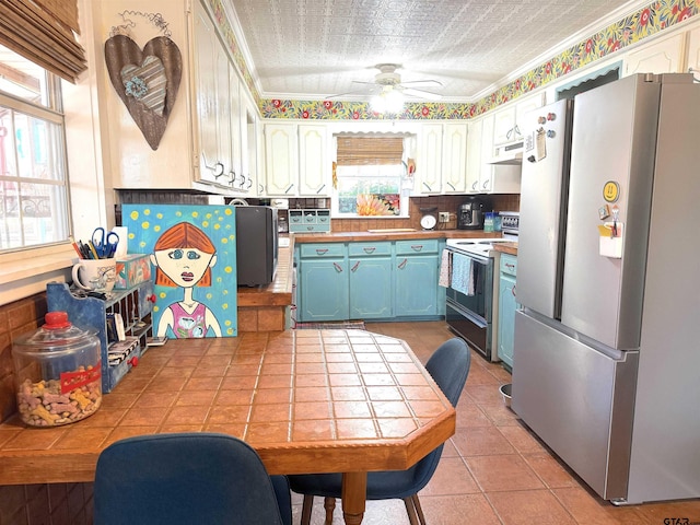 kitchen with blue cabinets, light tile patterned floors, range with electric stovetop, stainless steel fridge, and white cabinets