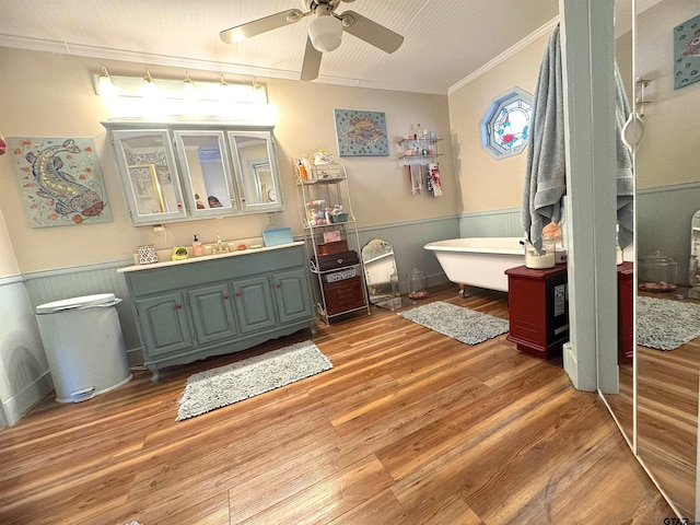 bathroom with ceiling fan, hardwood / wood-style floors, vanity, ornamental molding, and a tub to relax in