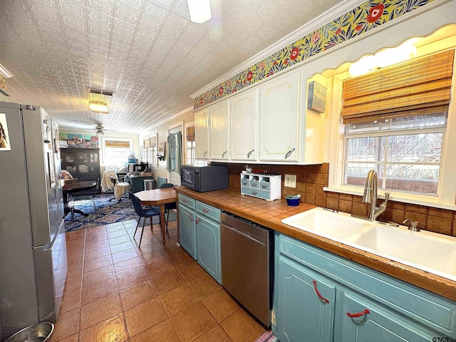 kitchen with white cabinets, an ornate ceiling, open floor plan, stainless steel appliances, and a sink