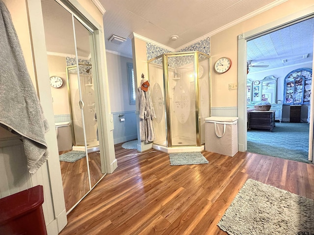 bathroom with hardwood / wood-style floors, crown molding, and a shower with door