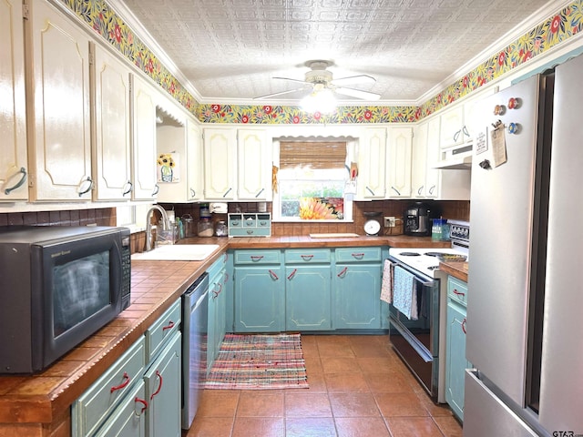 kitchen featuring appliances with stainless steel finishes, white cabinetry, sink, backsplash, and ceiling fan