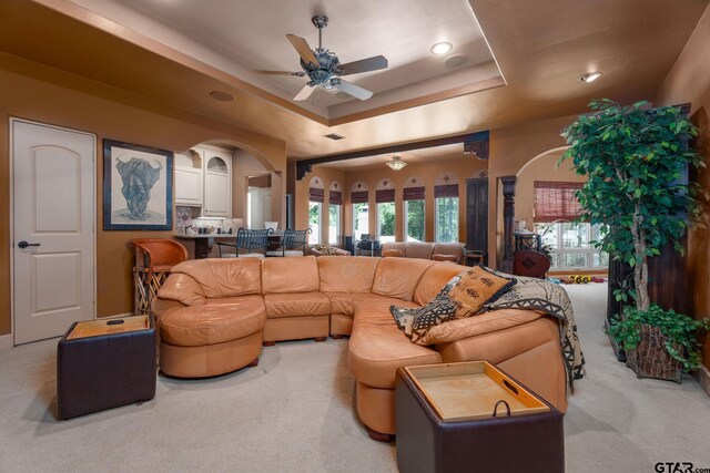 carpeted living room featuring a tray ceiling and ceiling fan