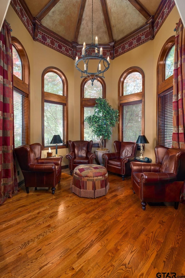 living room with wood-type flooring, high vaulted ceiling, and a chandelier