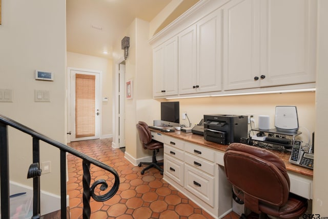 office with dark tile patterned floors and built in desk