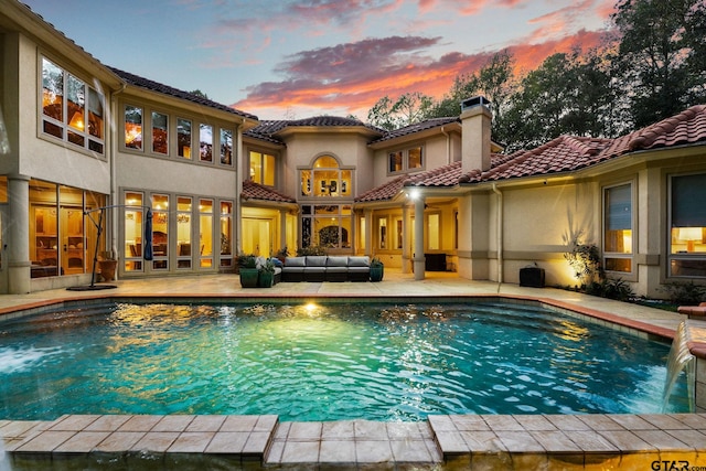 pool at dusk with an outdoor hangout area