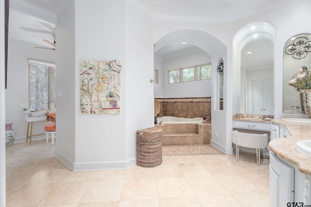 bathroom with tile patterned floors, vanity, ceiling fan, and a relaxing tiled tub