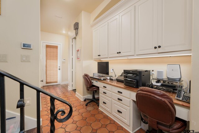 office space featuring built in desk and dark tile patterned flooring