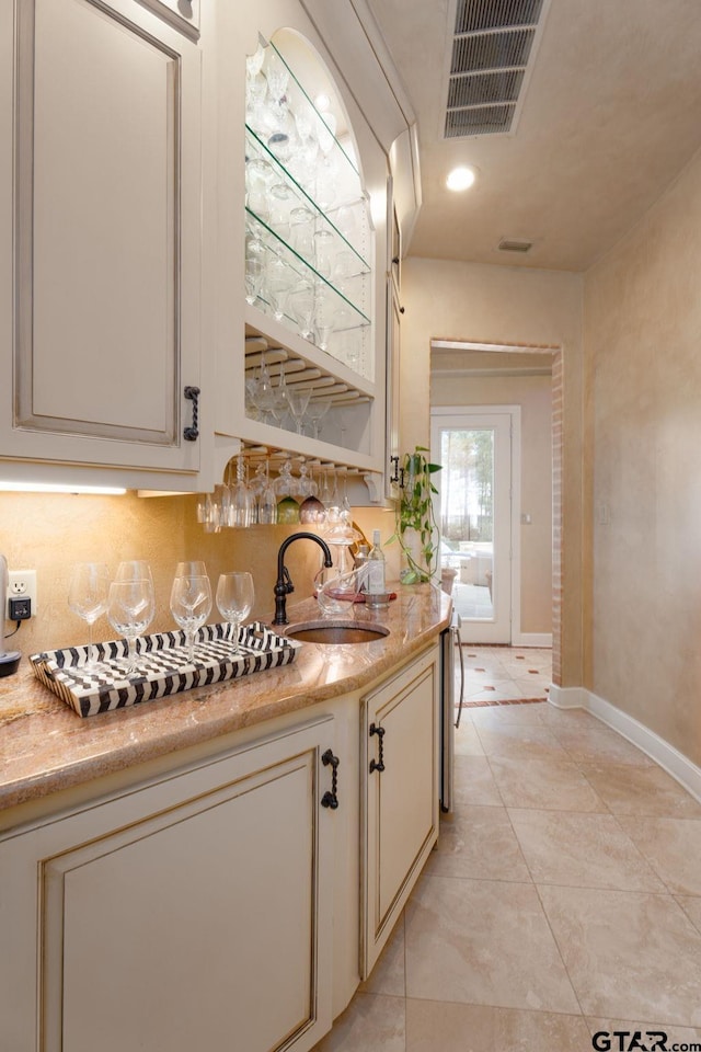 kitchen with backsplash, cream cabinets, sink, and light tile patterned floors