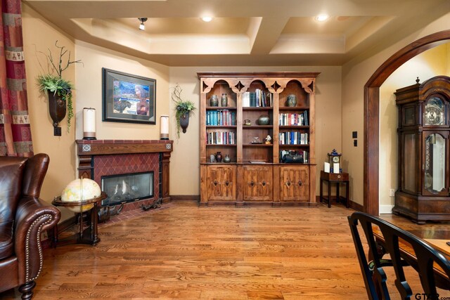 sitting room with a fireplace, a tray ceiling, and light hardwood / wood-style flooring