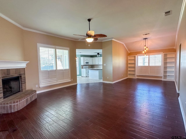 unfurnished living room with crown molding, ceiling fan, dark hardwood / wood-style flooring, and a brick fireplace