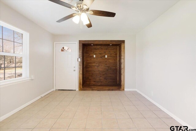 spare room featuring light tile patterned flooring, ceiling fan, and baseboards