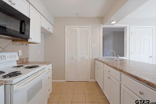kitchen featuring white range with electric cooktop, a sink, white cabinets, black microwave, and decorative backsplash