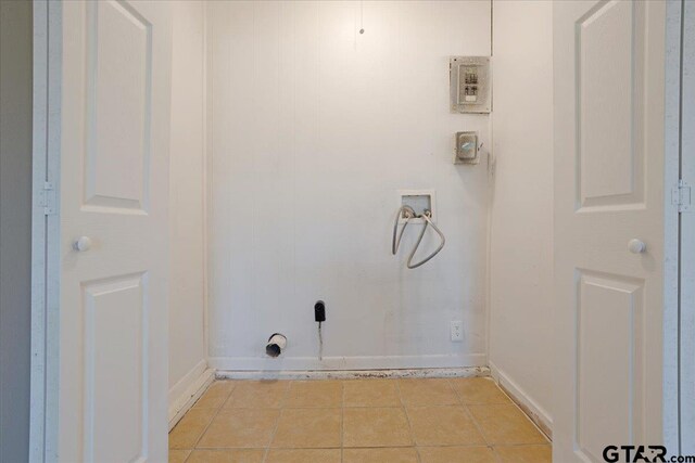 clothes washing area with washer hookup, laundry area, light tile patterned floors, and baseboards