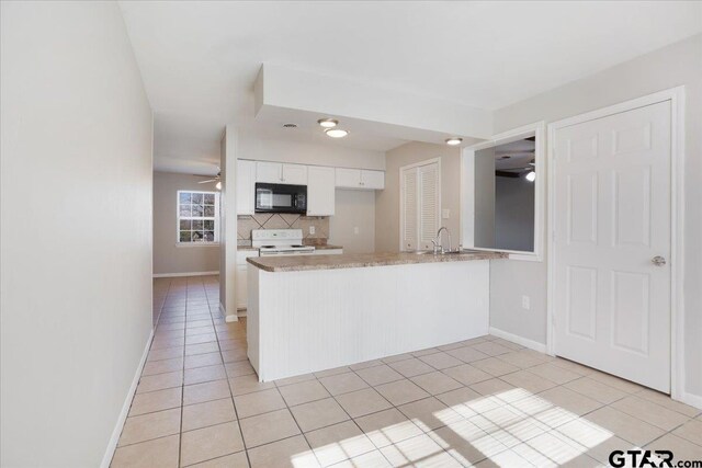 kitchen with light tile patterned floors, white range with electric cooktop, a peninsula, black microwave, and tasteful backsplash