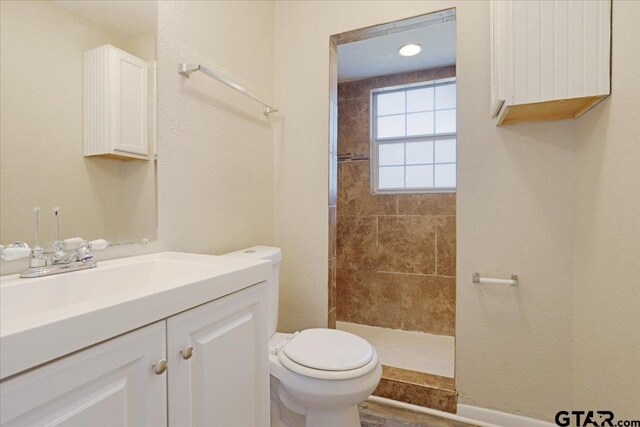 full bathroom with toilet, vanity, and a tile shower